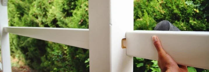 Person baut einen weißen Holzzaun